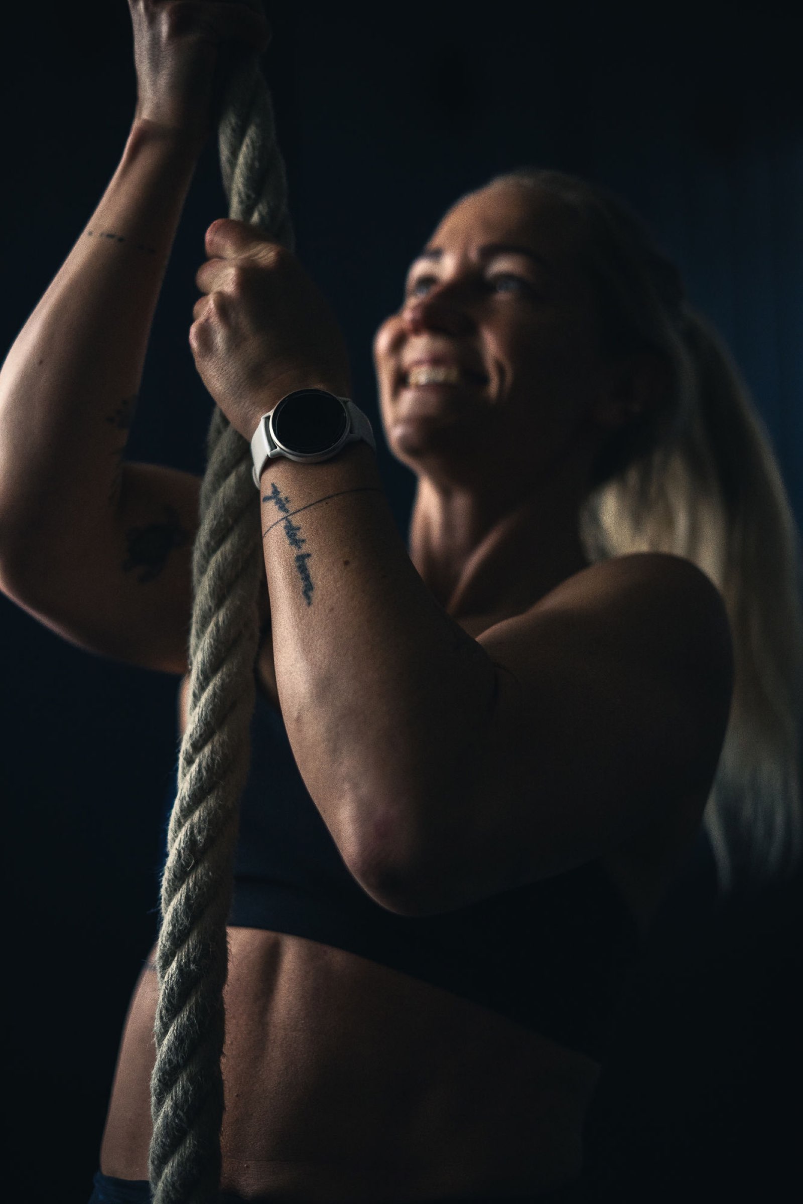 Smiling female athlete on the rope with her Garmin watch, training data flowing into Movement Rebels