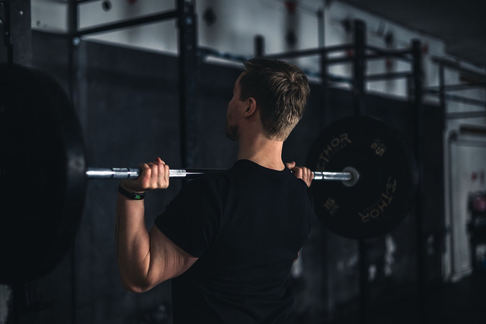 Athlete unracking a barbell for back squats in a Movement Rebels gym session