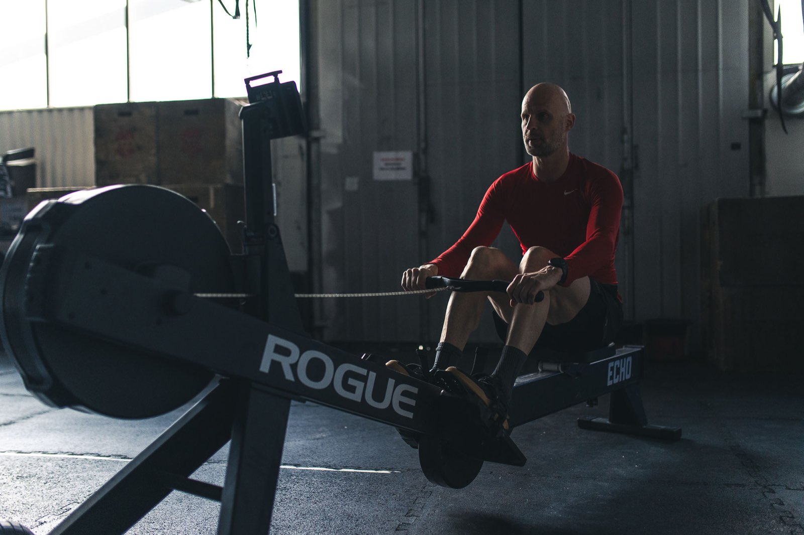 Masters athlete mid drive on the rowing erg during a Movement Rebels endurance session in an industrial gym