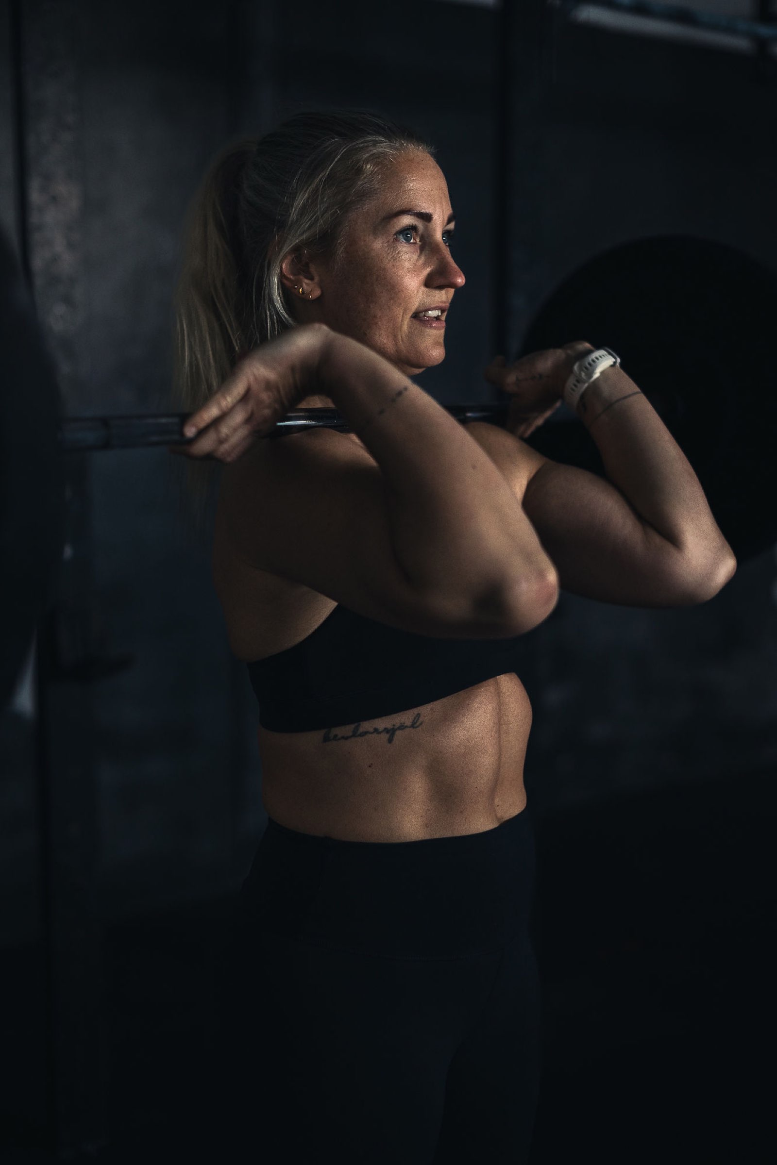 Confident female athlete under the barbell in a Movement Rebels strength session
