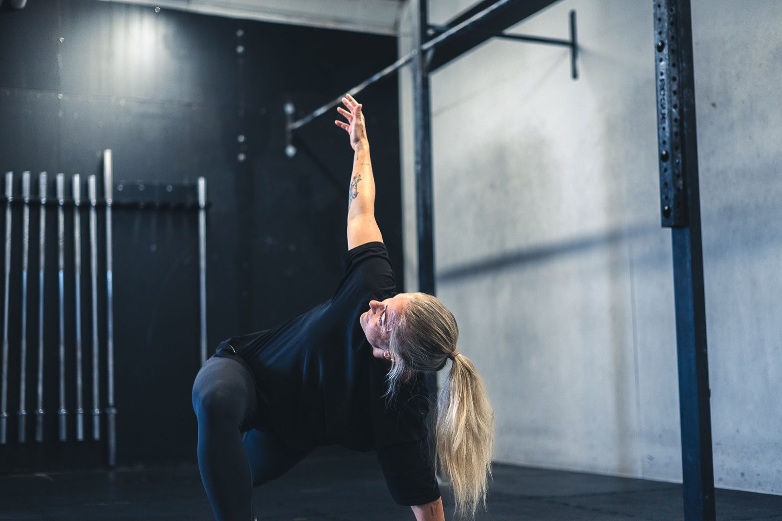 Athlete flowing through a deep lunge mobility stretch during a Movement Rebels warm-up in a dark garage gym