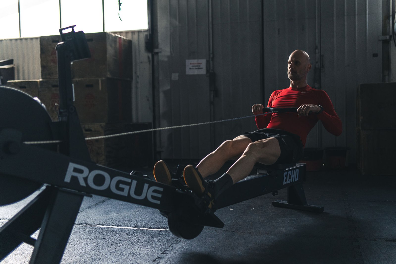 Athlete leaning back at the finish of a rowing stroke in a Movement Rebels garage gym