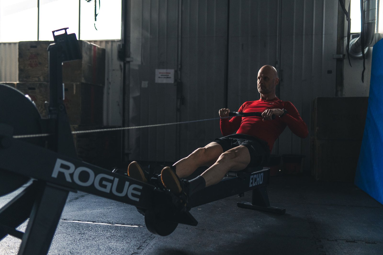 Rowing intervals in a dark industrial gym during a Movement Rebels conditioning workout